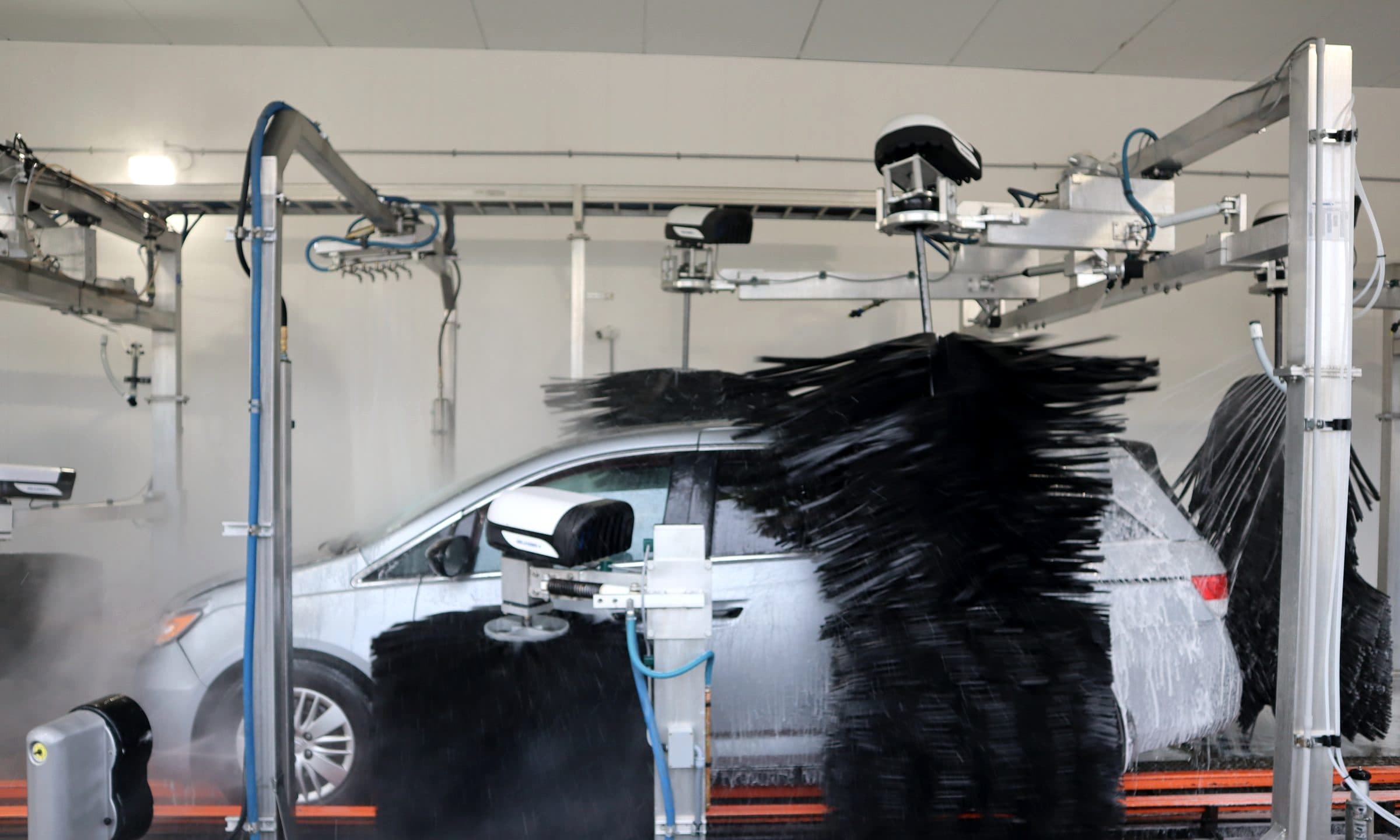 A vehicle passing through tunnel wash equipment.